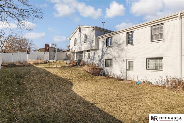 rear view of property with a lawn and a trampoline