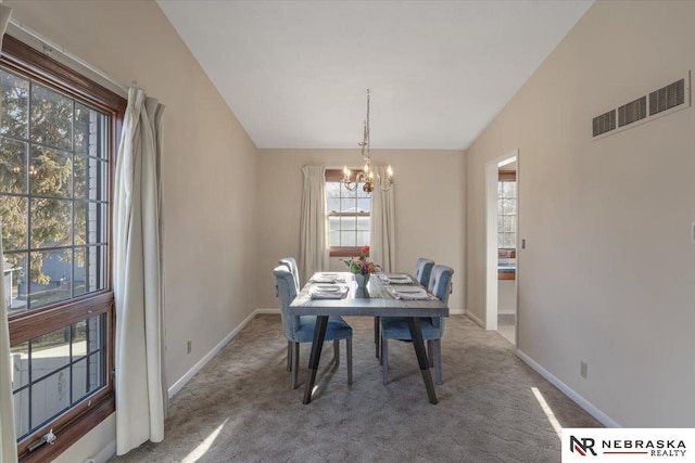 carpeted dining room with vaulted ceiling and an inviting chandelier