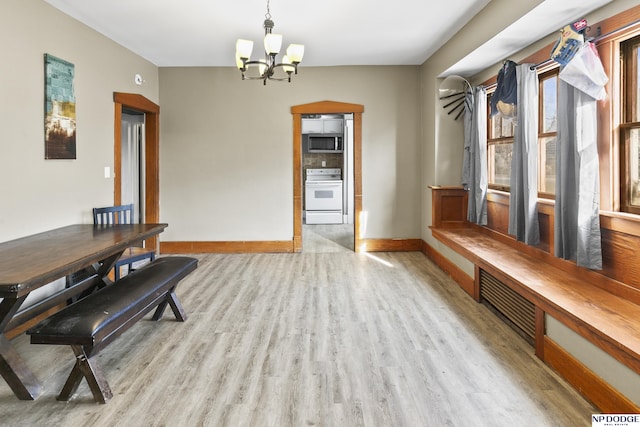 dining space with light wood-type flooring and an inviting chandelier