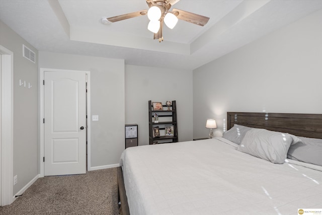 bedroom featuring ceiling fan, carpet floors, and a tray ceiling