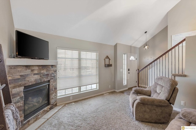 living room with a wealth of natural light, lofted ceiling, and a stone fireplace