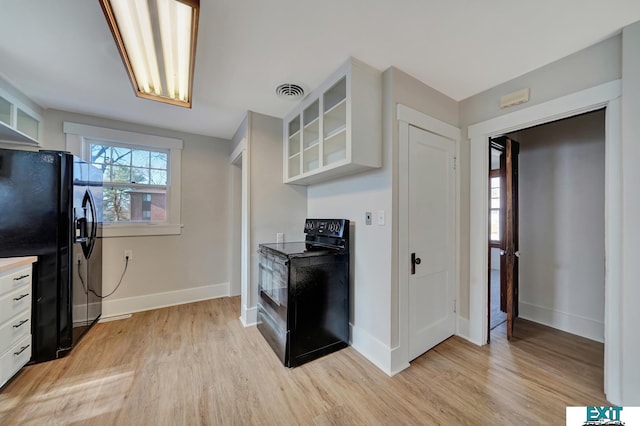 kitchen with light hardwood / wood-style flooring, white cabinets, and black appliances