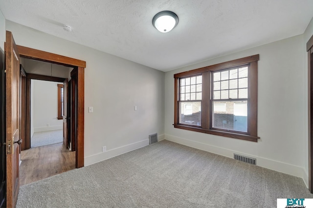 unfurnished room with carpet floors and a textured ceiling