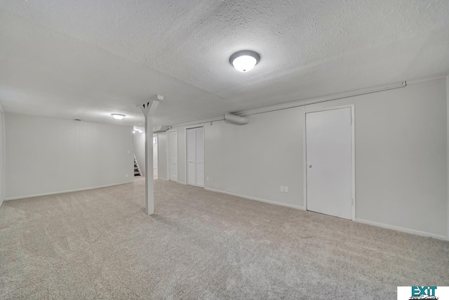 basement featuring light carpet and a textured ceiling