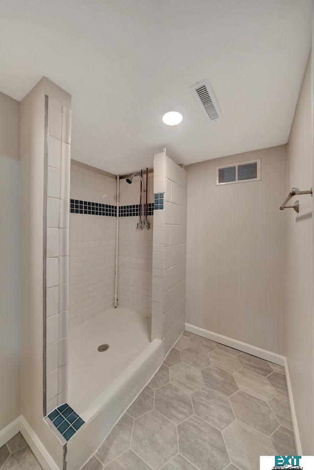 bathroom with tile patterned flooring and a tile shower