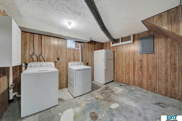 laundry room featuring independent washer and dryer, wooden walls, and electric panel