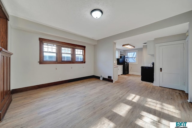 unfurnished living room featuring a wealth of natural light, light hardwood / wood-style flooring, and a textured ceiling