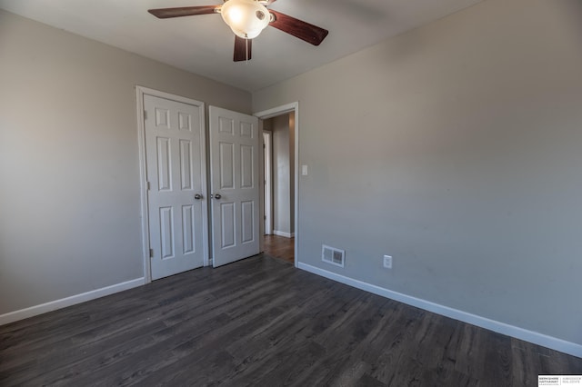 unfurnished bedroom featuring dark wood-type flooring, ceiling fan, and a closet