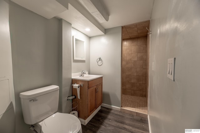 bathroom with toilet, vanity, wood-type flooring, and tiled shower