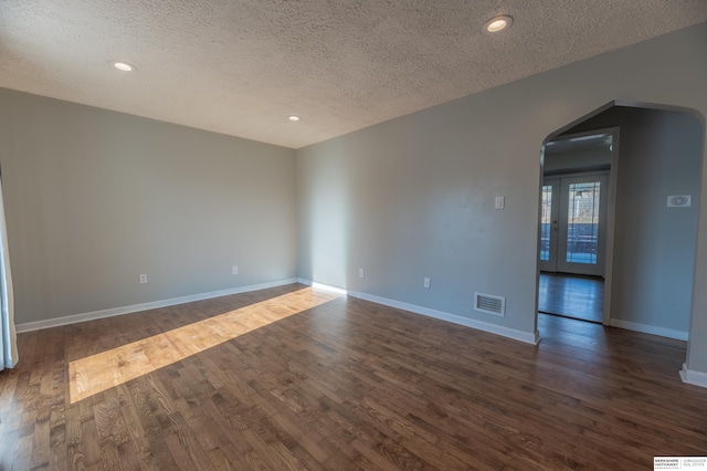 empty room with a textured ceiling and dark wood-type flooring