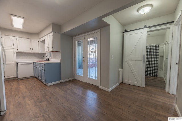 kitchen with tasteful backsplash, a barn door, dishwasher, dark hardwood / wood-style floors, and white cabinets