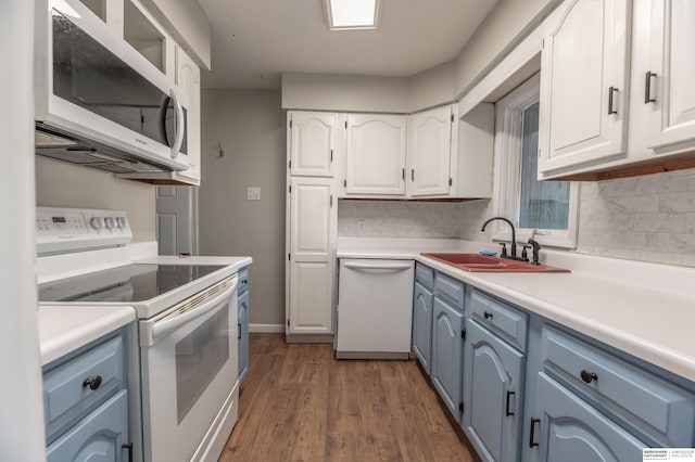 kitchen with dark wood-type flooring, sink, white appliances, and white cabinetry