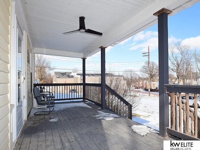 snow covered deck featuring ceiling fan and covered porch