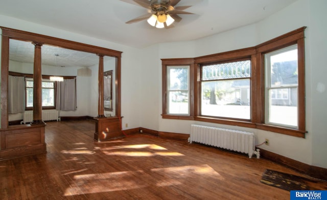 spare room featuring ceiling fan, dark hardwood / wood-style floors, radiator heating unit, and decorative columns