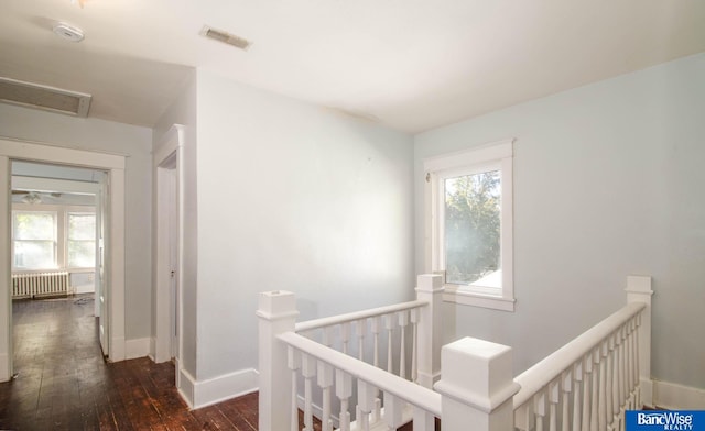 corridor with plenty of natural light, dark hardwood / wood-style floors, and radiator heating unit