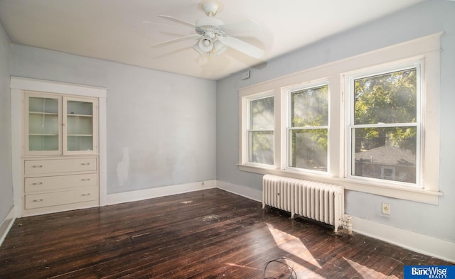 empty room featuring ceiling fan, dark hardwood / wood-style flooring, and radiator heating unit