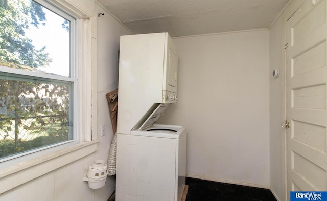 clothes washing area with crown molding, stacked washer and clothes dryer, and plenty of natural light