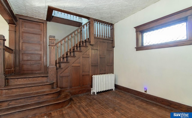 staircase with wood-type flooring and radiator heating unit