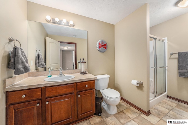 bathroom featuring vanity, toilet, a textured ceiling, and walk in shower