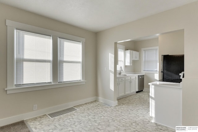 kitchen featuring appliances with stainless steel finishes, a wealth of natural light, white cabinetry, and sink