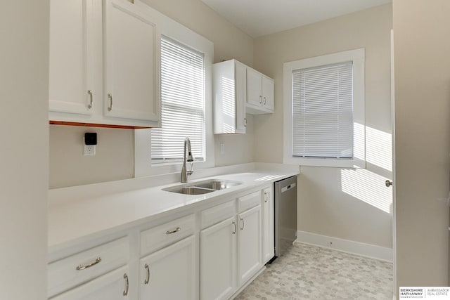 kitchen with stainless steel dishwasher, sink, and white cabinetry