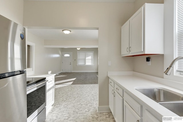 kitchen with light colored carpet, sink, stainless steel appliances, and white cabinetry