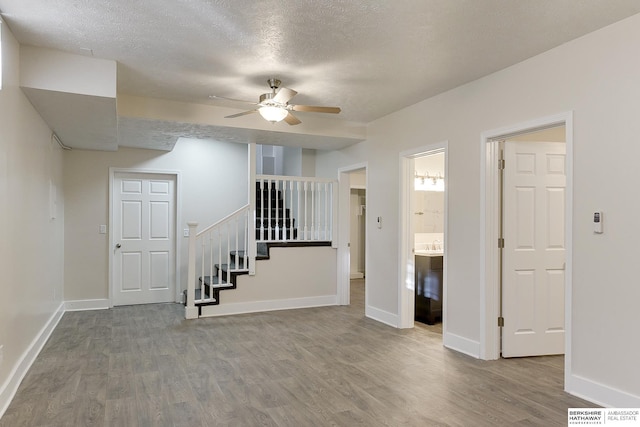 interior space with a textured ceiling, ceiling fan, and wood-type flooring