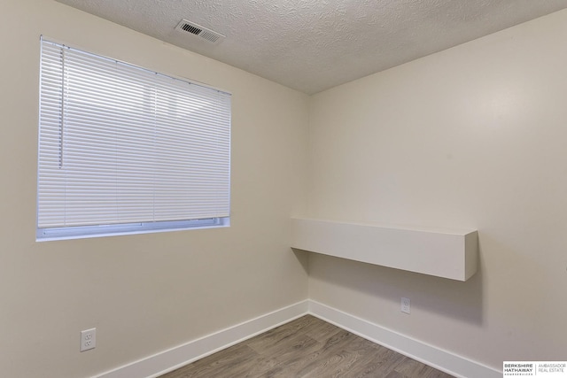 unfurnished room featuring wood-type flooring and a textured ceiling