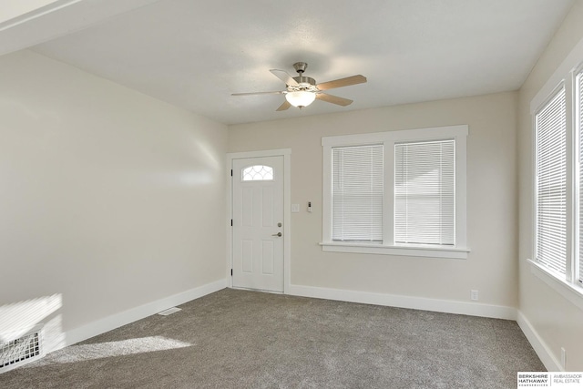 entryway with ceiling fan, a wealth of natural light, and carpet