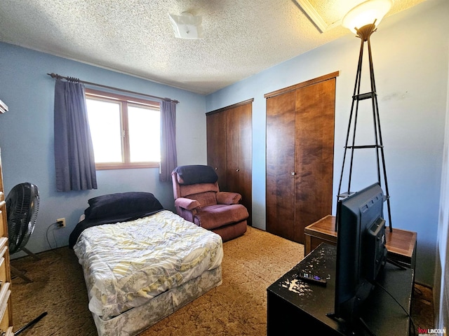 carpeted bedroom featuring multiple closets and a textured ceiling