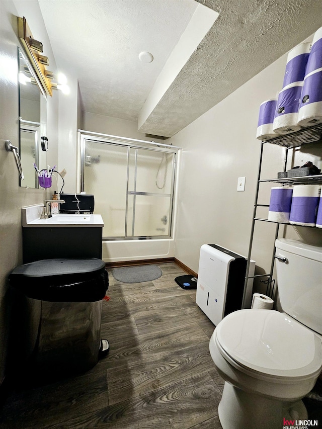 bathroom featuring wood-type flooring, a shower with door, toilet, and a textured ceiling