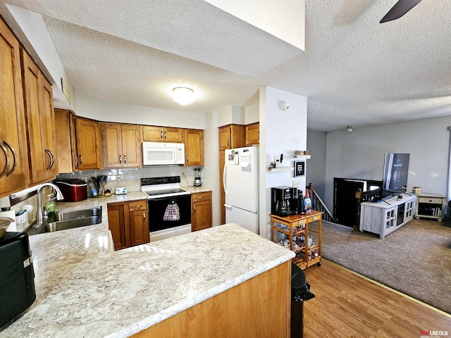 kitchen with sink, tasteful backsplash, light wood-type flooring, kitchen peninsula, and white appliances