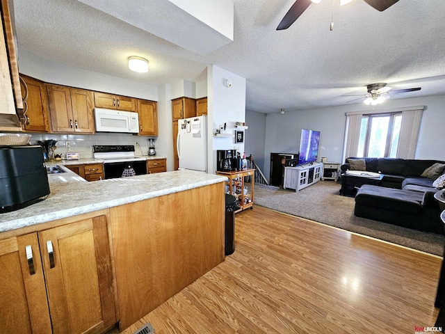 kitchen with white appliances, light hardwood / wood-style flooring, backsplash, a textured ceiling, and kitchen peninsula