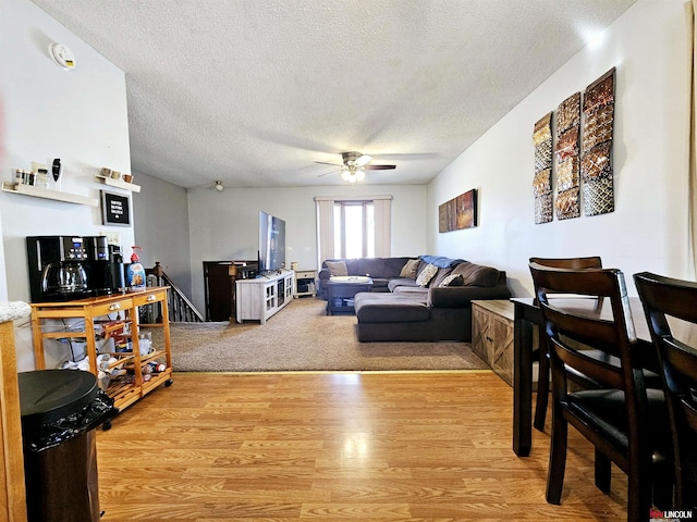 living room with ceiling fan, light hardwood / wood-style flooring, and a textured ceiling