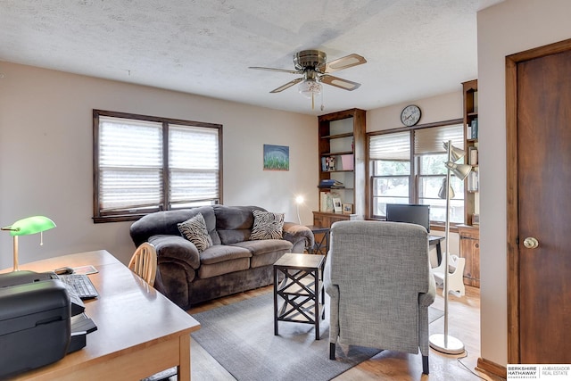 living room featuring a textured ceiling, ceiling fan, and a wealth of natural light