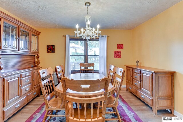 dining area featuring a textured ceiling, an inviting chandelier, and light hardwood / wood-style flooring