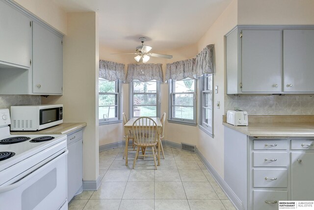 kitchen featuring ceiling fan, light tile patterned flooring, gray cabinetry, and white appliances