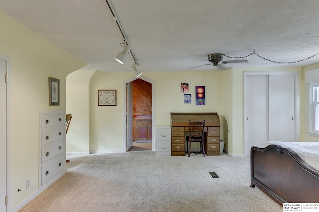 unfurnished bedroom featuring light carpet, ceiling fan, ensuite bathroom, and track lighting