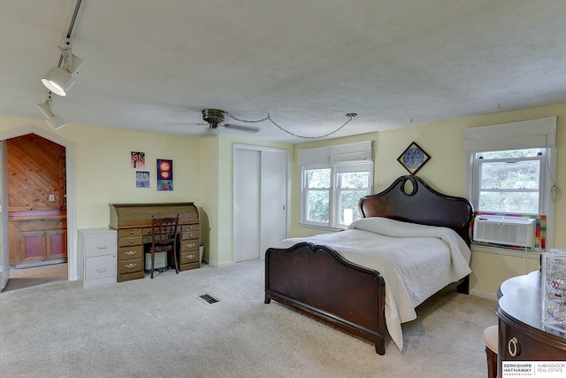 bedroom with ceiling fan, rail lighting, light colored carpet, and multiple windows