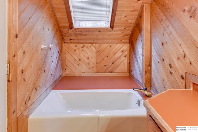 bathroom with a bath, vanity, and wooden walls