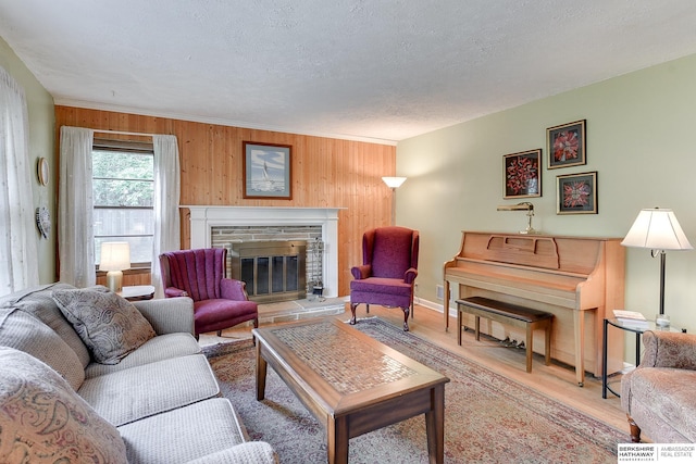 living room featuring a textured ceiling, a brick fireplace, wood-type flooring, and wooden walls