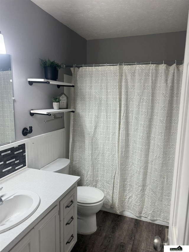 bathroom with hardwood / wood-style flooring, a textured ceiling, toilet, and vanity