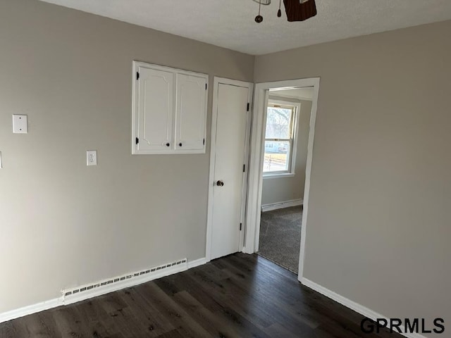 spare room with ceiling fan, baseboard heating, a textured ceiling, and dark hardwood / wood-style flooring