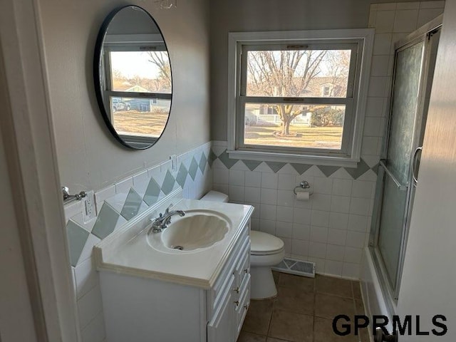 bathroom with tile patterned flooring, tile walls, plenty of natural light, and walk in shower