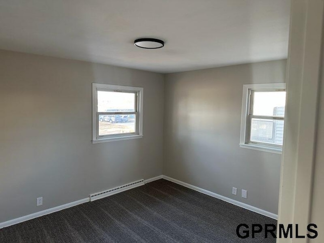 unfurnished room with a baseboard radiator, a wealth of natural light, and dark colored carpet