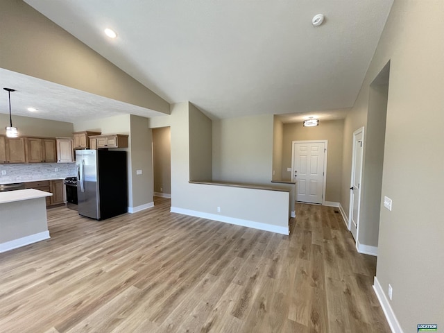 kitchen with decorative backsplash, freestanding refrigerator, lofted ceiling, and light wood finished floors