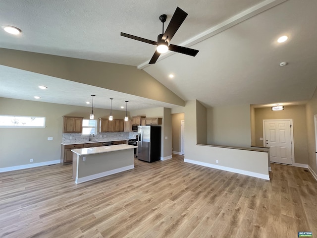 kitchen with tasteful backsplash, light wood-style flooring, appliances with stainless steel finishes, open floor plan, and a kitchen island