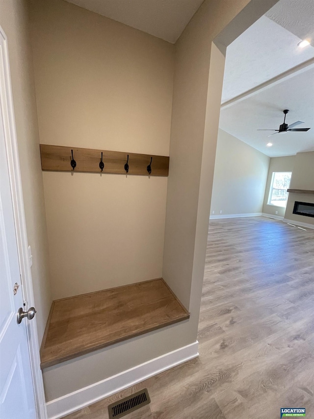 mudroom with baseboards, visible vents, a ceiling fan, a glass covered fireplace, and wood finished floors