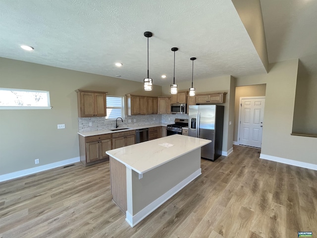 kitchen featuring light wood finished floors, baseboards, decorative backsplash, appliances with stainless steel finishes, and a sink