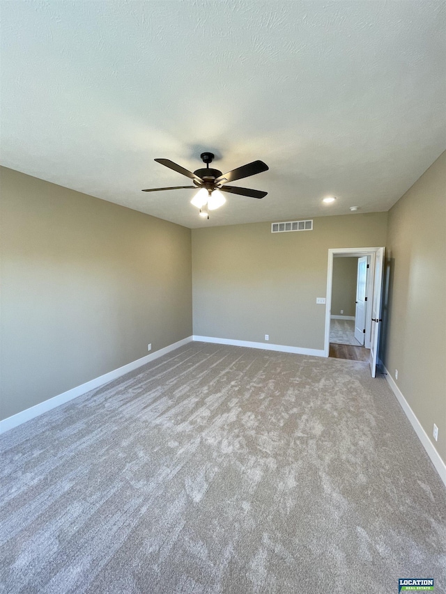 empty room featuring a textured ceiling, carpet flooring, a ceiling fan, visible vents, and baseboards